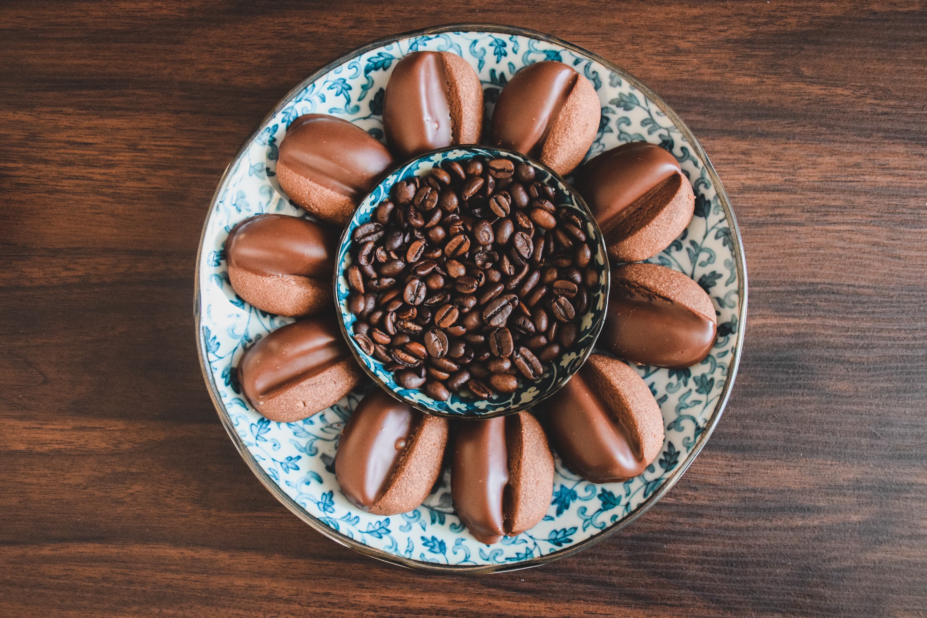 Chocolate-dipped coffee biscuits arranged around coffee beans on a plate